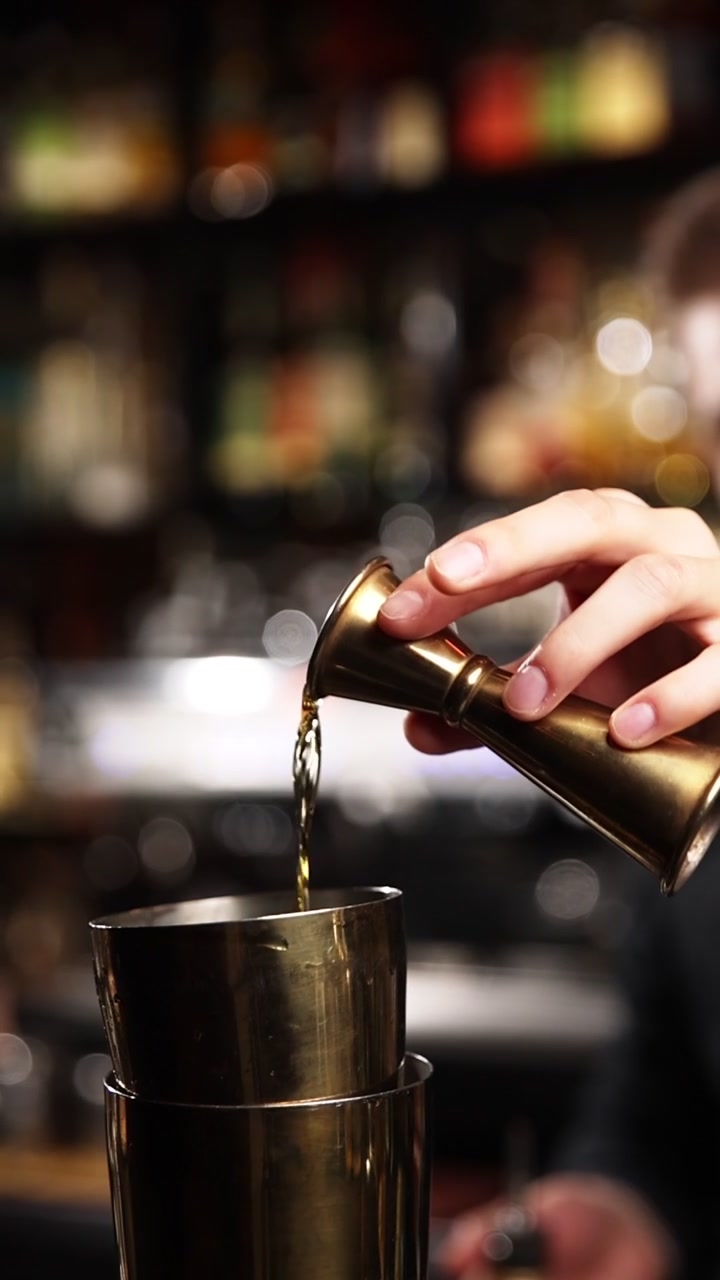 Barman professionista che misura e versa alcol con un jigger