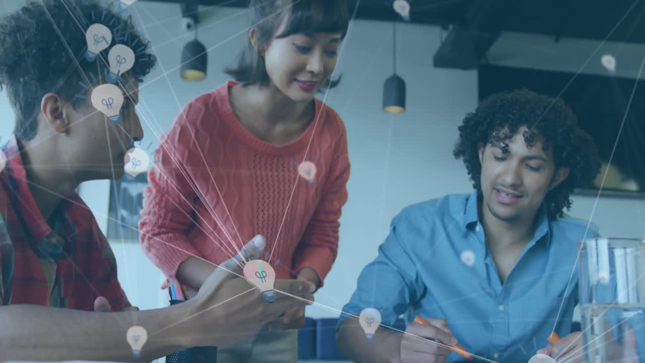 Animation of network of bulb icons over diverse colleagues discussing over a document at office