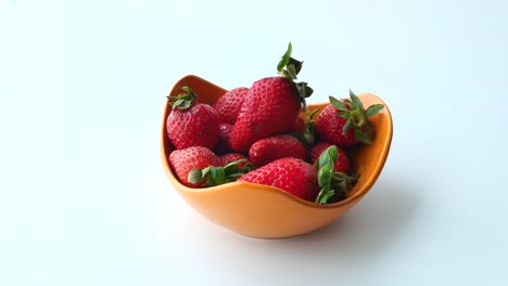 hand picking strawberries from a bowl