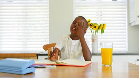 Vista-Frontal-De-Un-Niño-Negro-Haciendo-Los-Deberes-En-La-Mesa-Del-Comedor-En-Una-Casa-Cómoda-4k