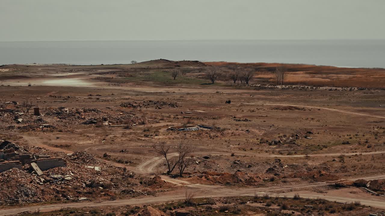 Desolate Coastal Landscape with Rubble and Vehicle Driving on Dirt Road
