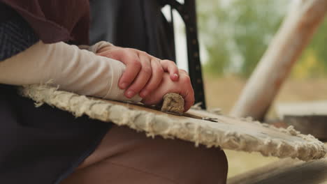 young woman sits holding round wooden shield on lap