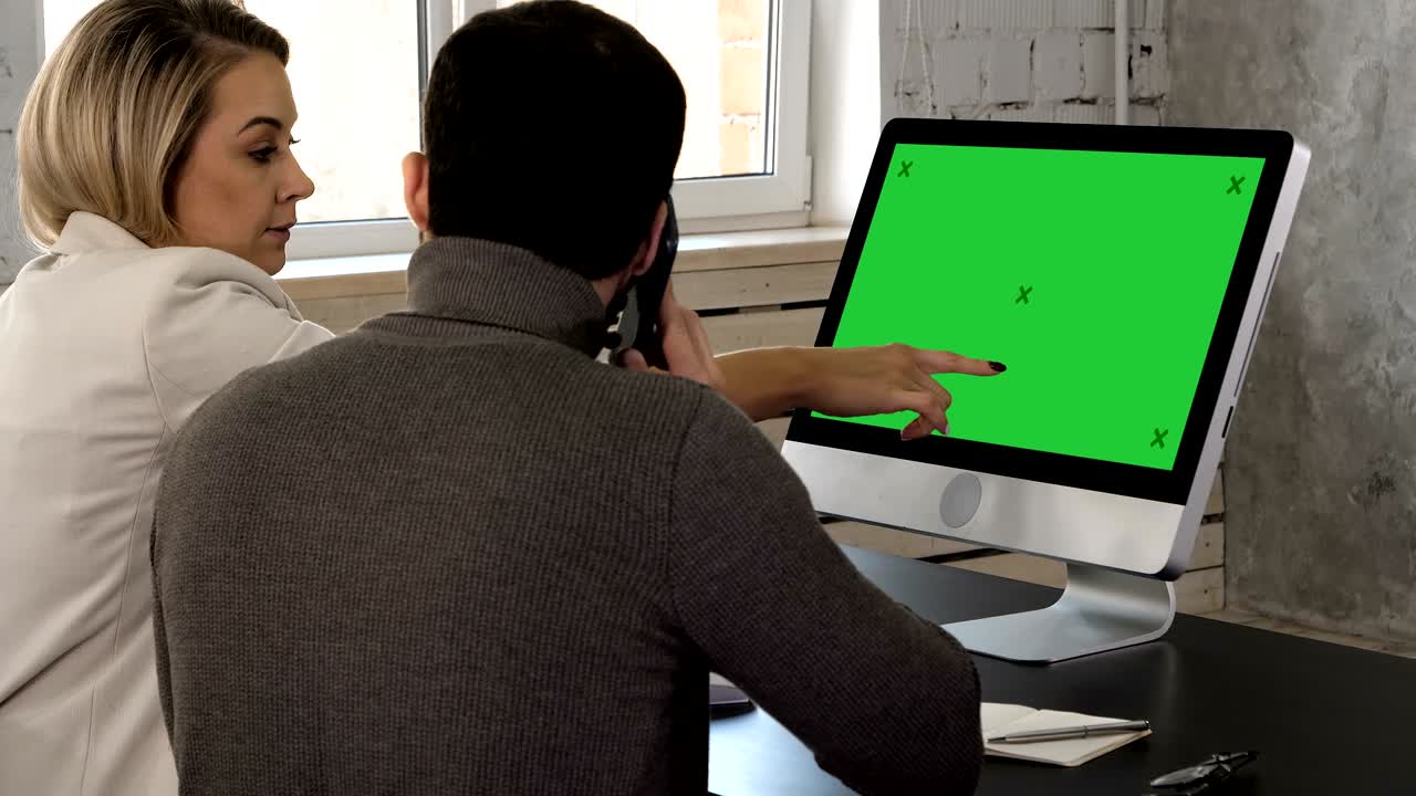 una pareja joven mirando el monitor hablando. el hombre hace una llamada. muestra de pantalla verde