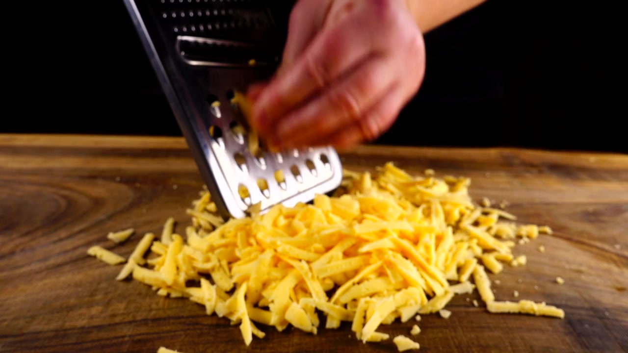 Lo chef strofina formaggio grattugiato su un tagliere