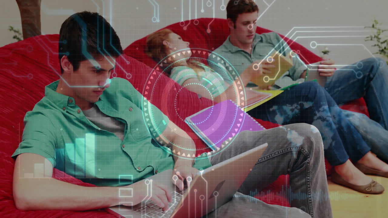 Friends sitting on beanbag couch typing on laptop in technology hub, with animated graph overlays