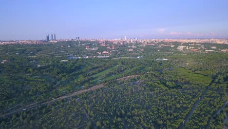 Madrid-skyline-viewed-over-green-canopies-from-city's-verdant-edge,-journey-at-dawn