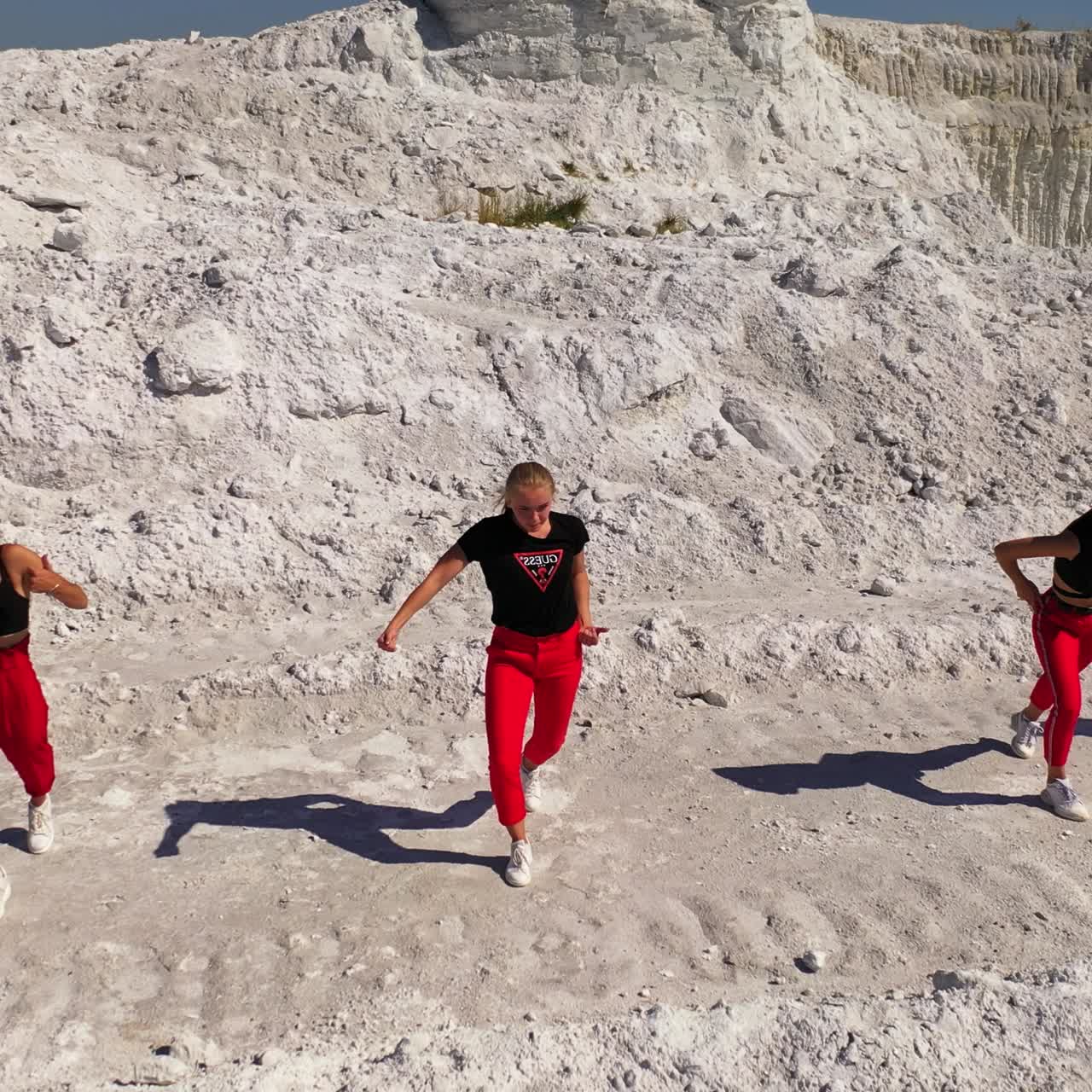 Six girls standing in a raw moving actively performing a dance. Drone footage rising over the female dance band