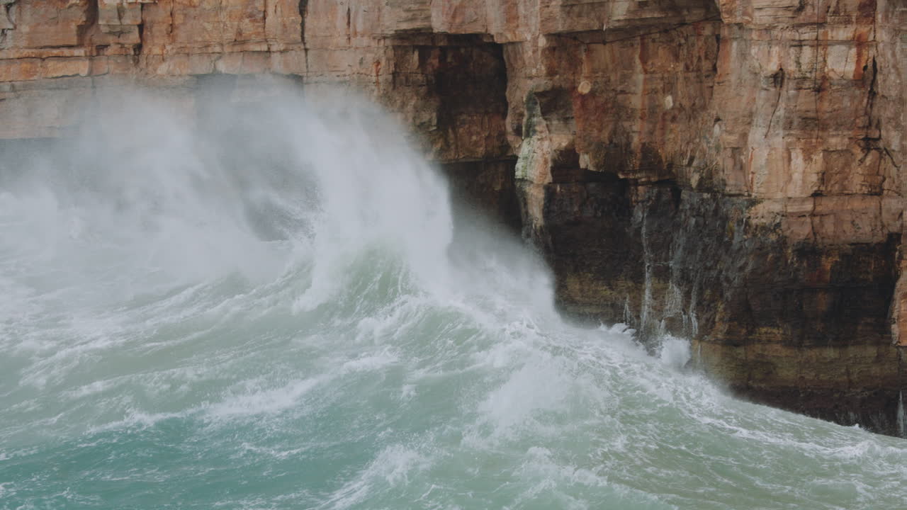 Waves crashing on the cliffs of Polignano a Mare during a storm in Adriatic Sea. Slowmotion 4k 120fps - panning right