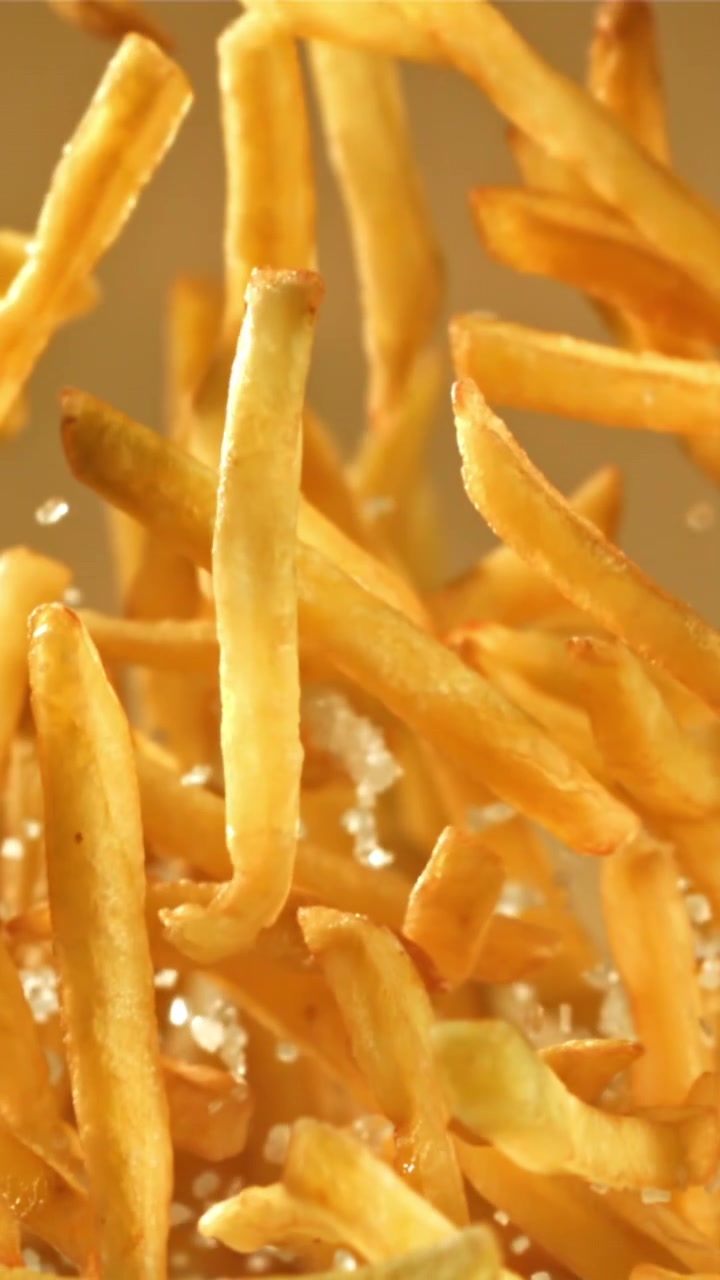 Gyllene krispiga pommes frites och salt som faller i slow motion.