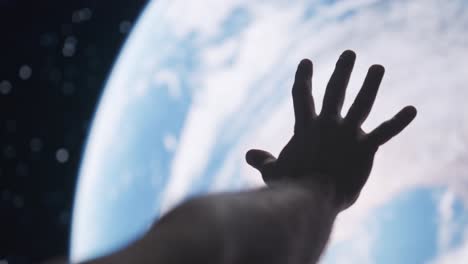 mano humana extendiéndose hacia la tierra desde el espacio