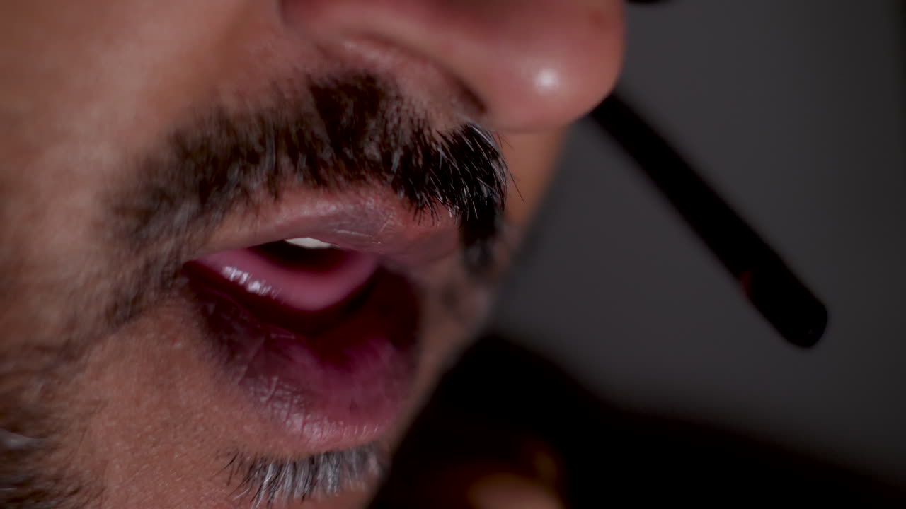 boca de un hombre asiático barbudo hablando con auriculares