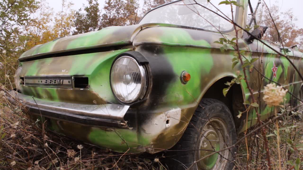 coche de estilo militar camuflado abandonado en la naturaleza
