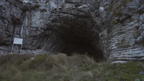 Approaching-drone-shot-at-the-entrance-of-the-Kozarnika-Cave,-an-archaeological-site-located-in-the-municipality-of-Dimovo,-in-Bulgaria