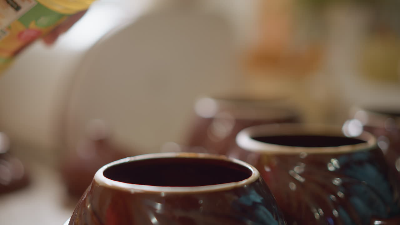 Rituale di versamento dell'olio. Recipienti di ceramica allineati su una superficie rustica. Scena illuminata dal sole di olio versato in ceramica. La luce del mattino illumina il versamento dell'olio in contenitori di argilla in un ambiente di cucina rustica.