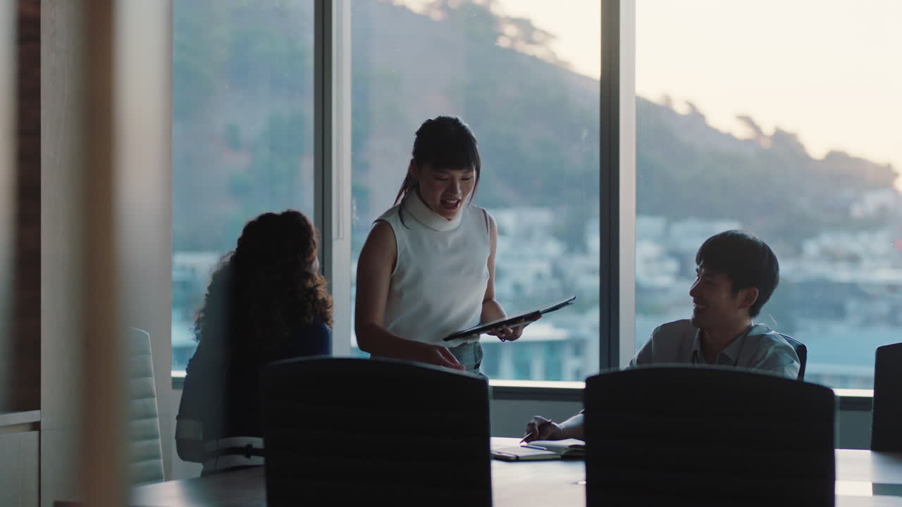 늦은 시간에 일하는 아시아 팀 리더 여성 동료들과 만나고 토론하는 프로젝트 관리자 태블릿 컴퓨터에서 아이디어를 공유하는 경영진 그룹 해가 지는 동안 사무실에서 브레인스토밍