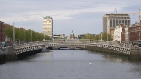 people cross at ha'penny bridge over liffey river in dublin, ireland