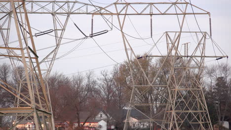 telephoto shot of electrical pylons with rural buildings in the background