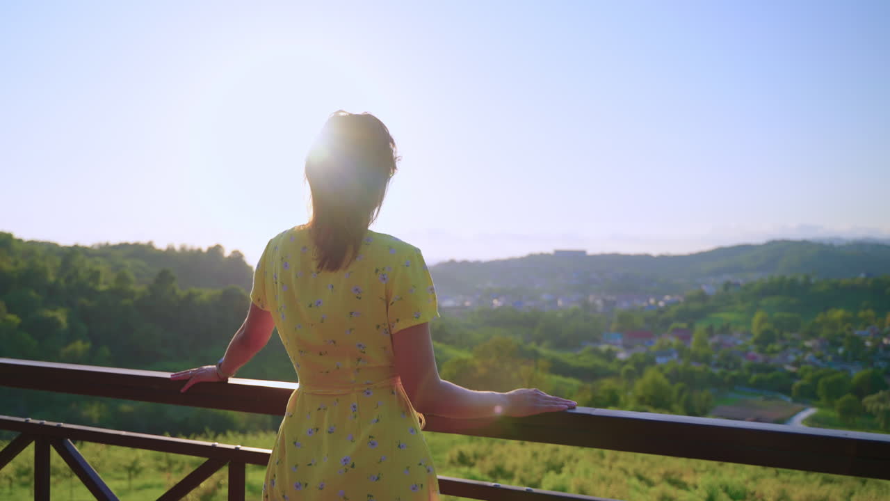 산꼭대기에서 해가 지는 풍경을 즐기는 여자.