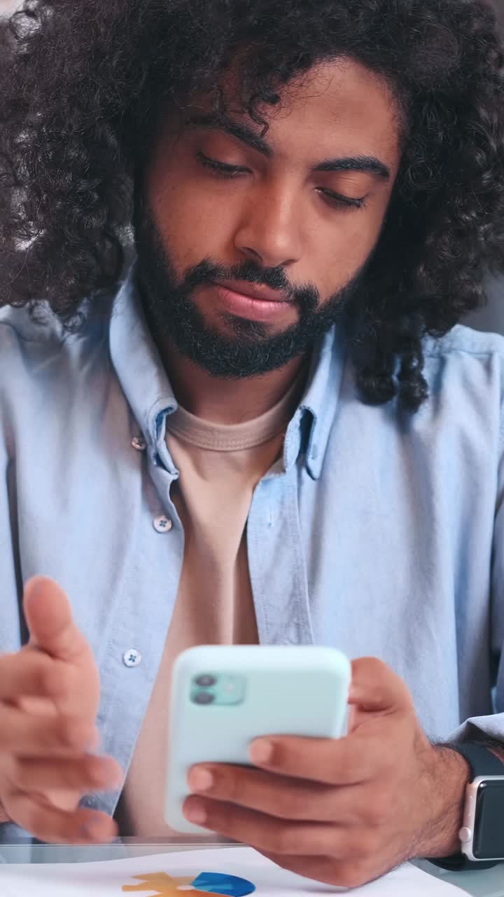 Engaged in conversation a man in a blue shirt using his phone at home