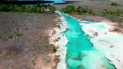 Aufschlussreiche-Drohnenaufnahme-Von-Menschen-Im-Klaren-Blauen-Wasser-Von-Bacalar,-Mexiko