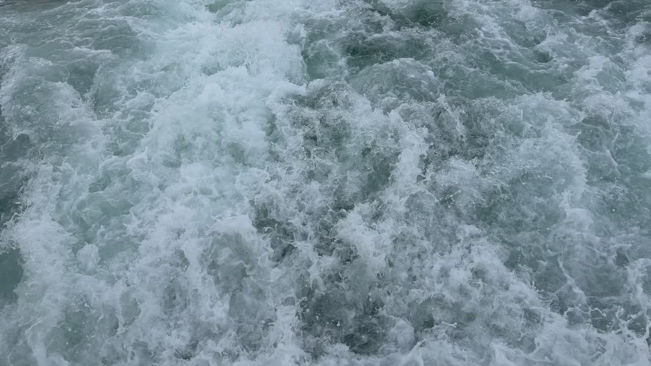 Ipnotizzante vista dall'alto al rallentatore di potenti onde oceaniche che si infrangono e si agitano. Splendida schiuma marina bianca dinamica e acqua che schizza creano uno sfondo astratto di natura marina.