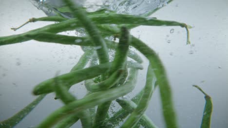 underwater view of beans thrown in water creating a spiral in clear water, slow-motion effect