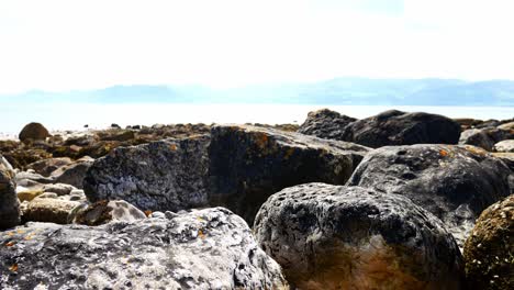 Bunte-Vielfalt-Von-Steinbrocken-Strandlandschaft-Unter-Nordwaleser-Bergkette-Steigender-Ausleger-Links