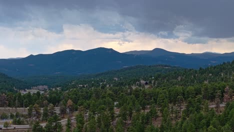 Aerial-pan-across-evergreen-forest-with-highway-dividing-the-trees-in-Colorado