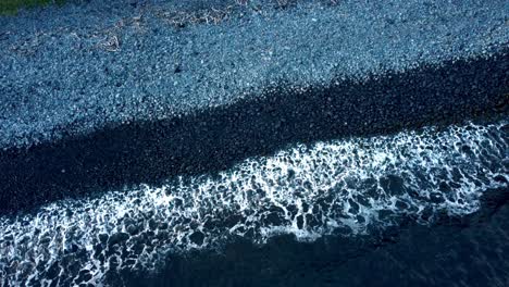 a drone view of east maui’s rocky shore offers a stunning contrast between the dark, jagged rocks and the sparkling pacific ocean, highlighting the island’s raw and untouched natural beauty