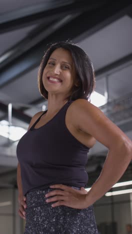 Vertical-Video-Portrait-Of-Smiling-Mature-Woman-Wearing-Fitness-Clothing-Standing-In-Gym-Ready-To-Exercise-3