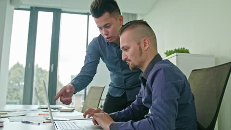 dos hombres discutiendo ideas usando una computadora portátil