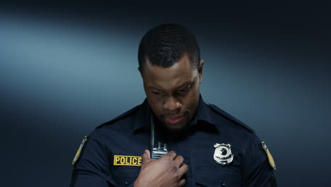 close up of the young policeman talking to the radio transmitter and listening while doing a work task