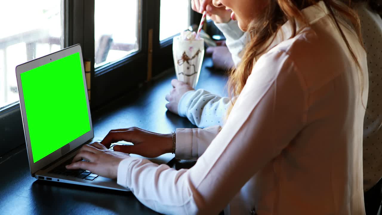 mujer sentada en un restaurante y usando una computadora portátil