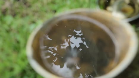 container with water with perfect reflection of foliage above is disturbed by a drop of water falling in