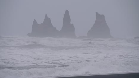 static, shot, of waves hitting a black cliffs, on the arctic sea, on a cloudy, stormy day, at diamond beach islandia, in south coast of iceland