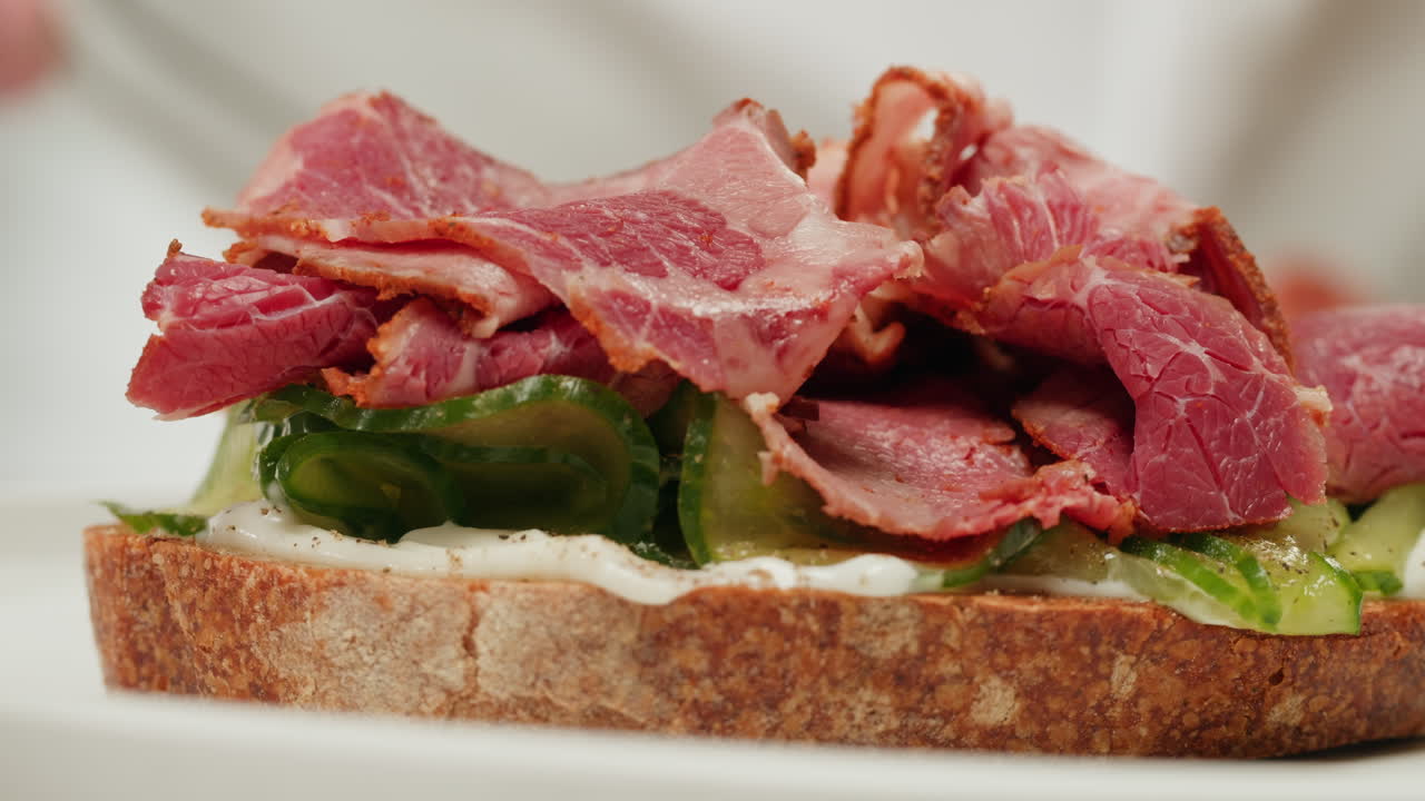 Close-up of a gourmet sandwich with smoked meat and cucumber