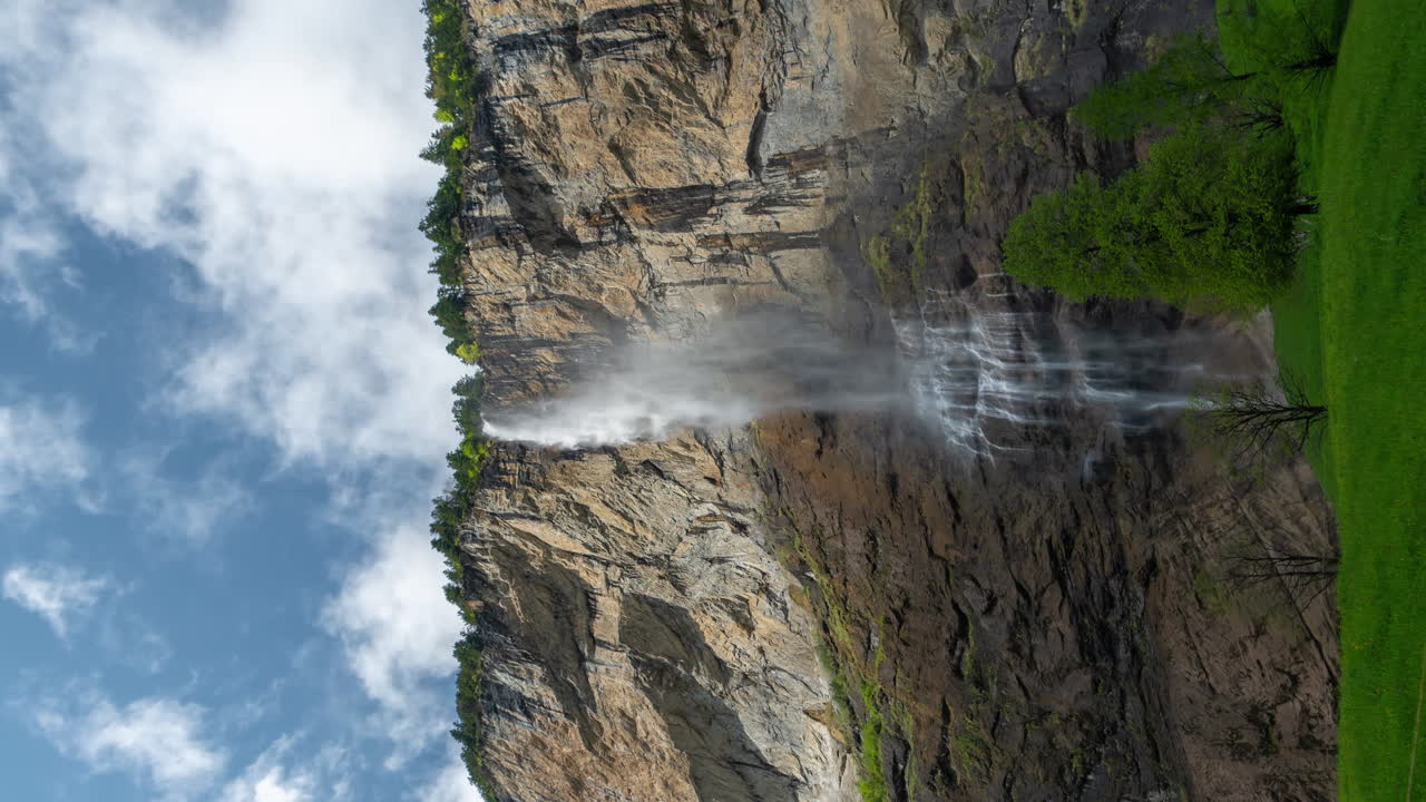 timelapse vertical de 4k, cascada en los alpes suizos, nubes y paisaje verde en primavera