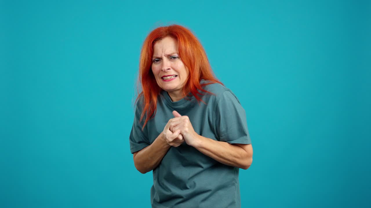 Woman with red hair expressing discomfort and pain against a blue background