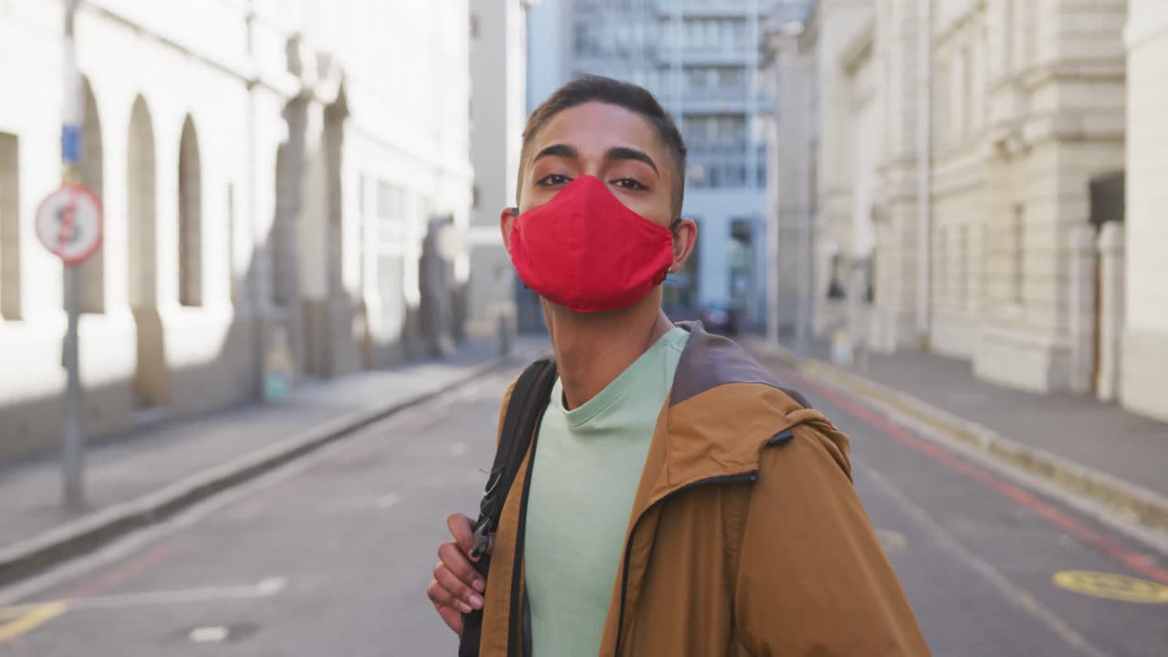 얼굴 마스크를 쓴 혼혈 남자가 거리에서 돌아다니고 있습니다.