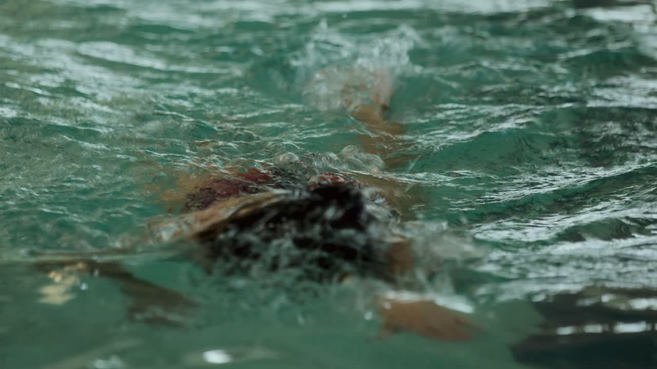A person swimming in a pool, creating splashes