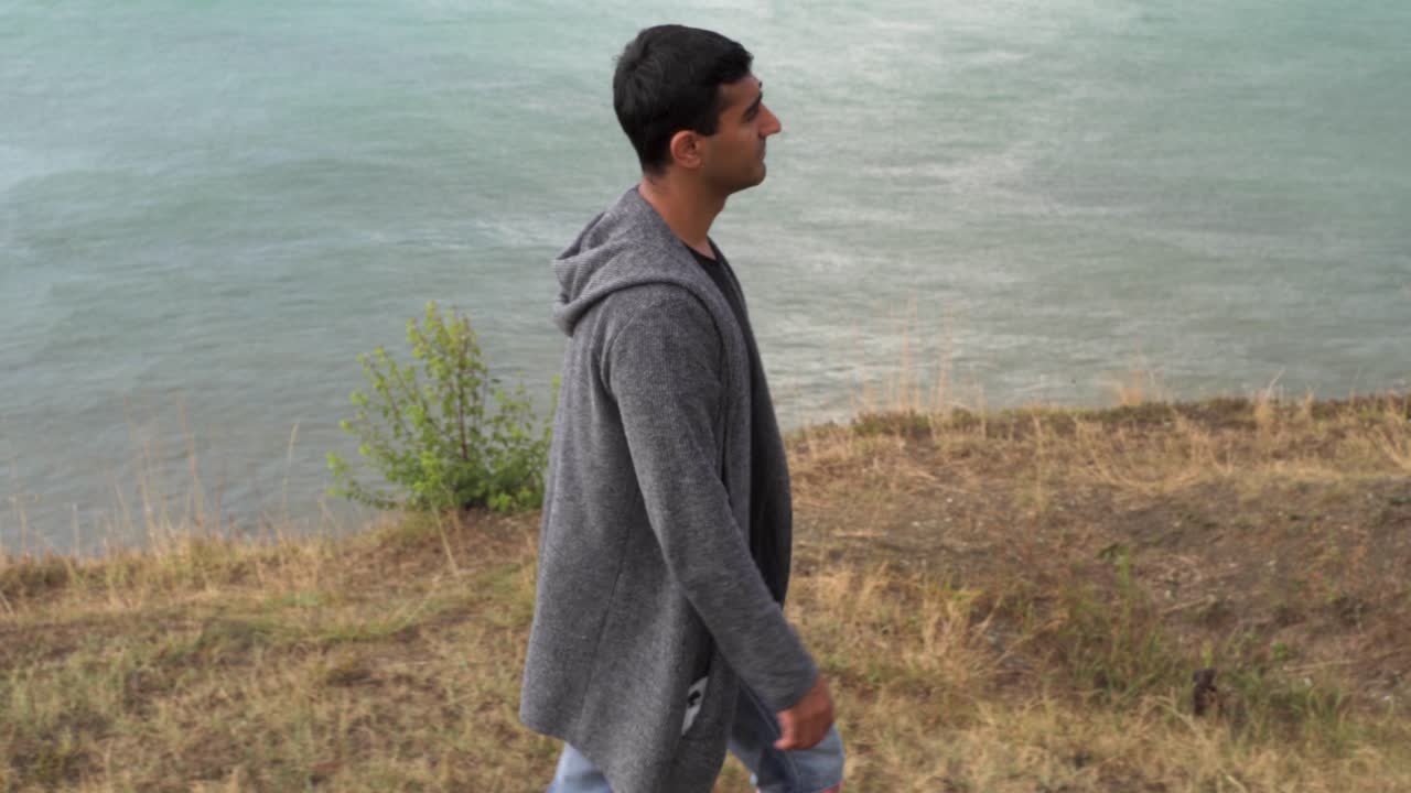 hombre caminando por un acantilado junto al mar