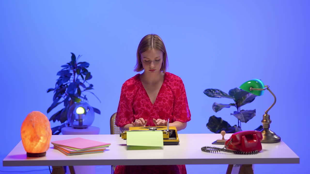 A focused woman types on a yellow typewriter at a colorful retro desk. Surrounded by pastel paper, a red phone, and nostalgic lighting, she creates in a calm and vintage-inspired workspace