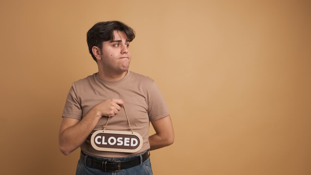 Sad man showing closed sign and gesturing in beige studio