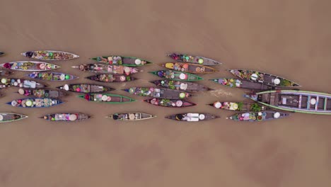 motorboat moving small wooden boats of traditional floating market on river, top down