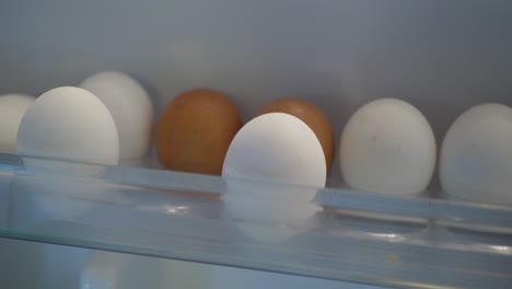 close up of white and brown eggs in a refrigerator