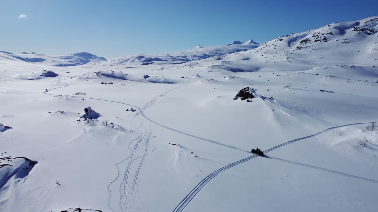 Splendida ripresa aerea con drone di un uomo che guida una motoslitta in un paesaggio artico innevato