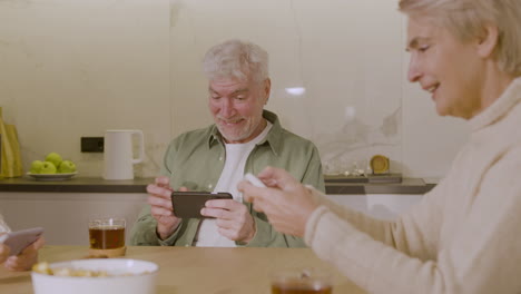 three senior friends playing game using their mobile phones at home