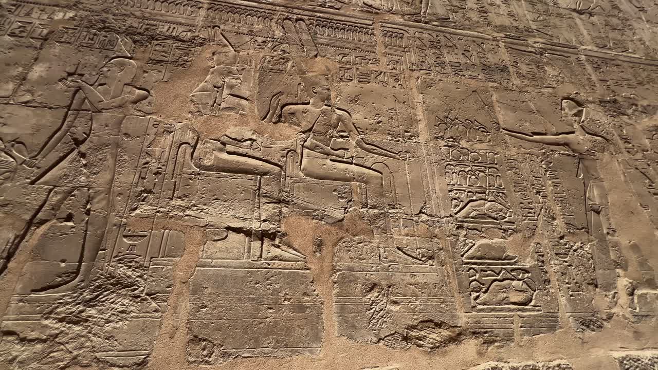 Panning shot of ancient Egyptian hieroglyphics carved into a stone wall at Karnak Temple, Luxor. For history, travel, or documentary use