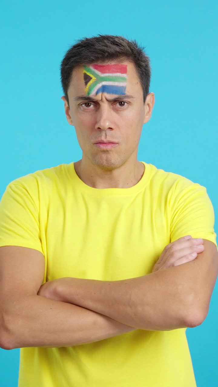 Dignified and serious man with south african flag painted on face