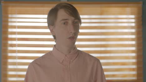 quirky man stood by a window reacting confused, static mid close up